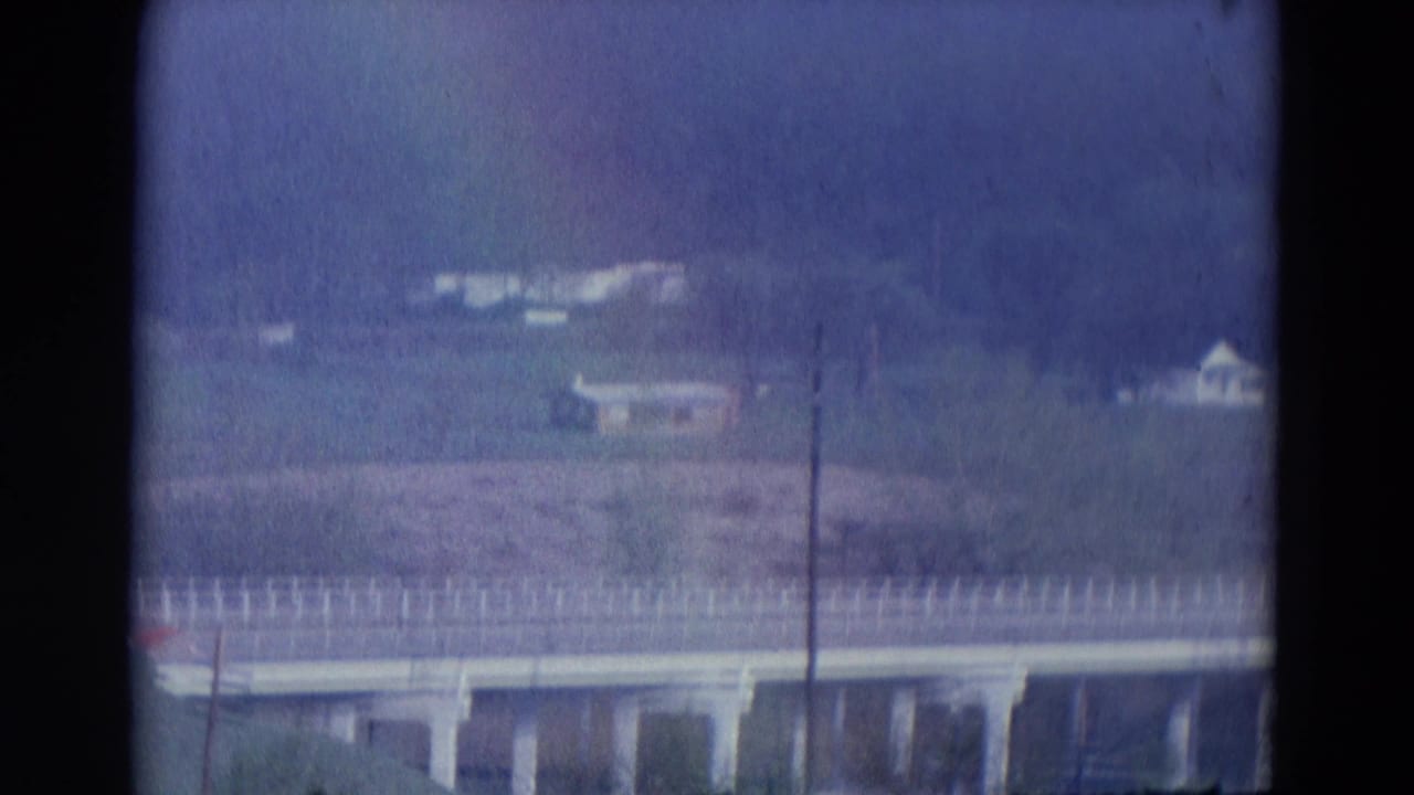Soft 8mm view of an elevated roadway or bridge, distant buildings, and open land in the 1969 Chicago-labeled home-movie clip.