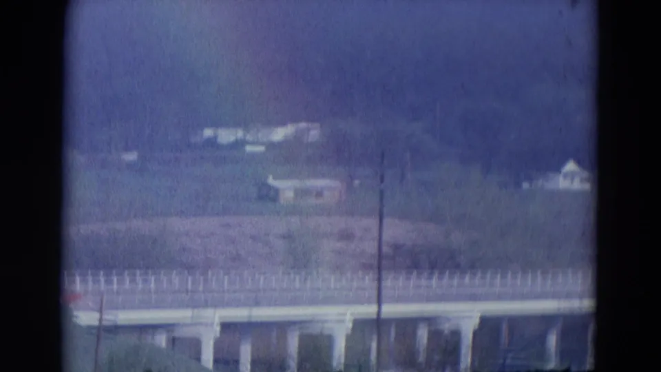 Soft 8mm view of an elevated roadway or bridge, distant buildings, and open land in the 1969 Chicago-labeled home-movie clip.
