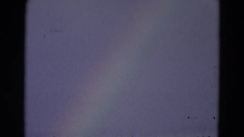 A soft rainbow segment fills the sky in this 1969 8mm Chicago-area frame, with little ground detail visible.