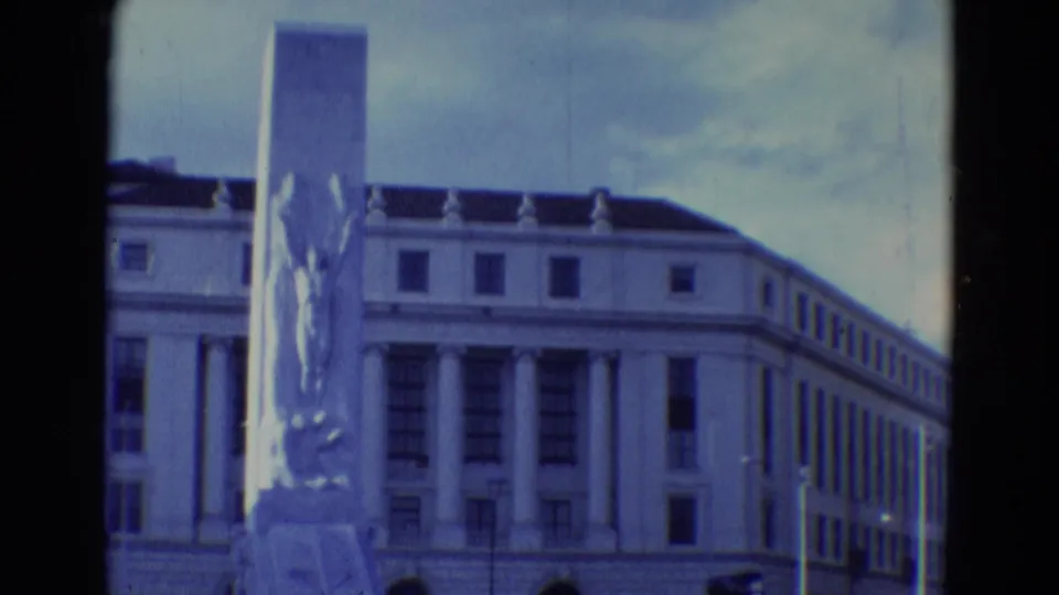 Final 1969 8mm frame from Diller, Nebraska holding on the public monument, columned facade, and cloudy sky.
