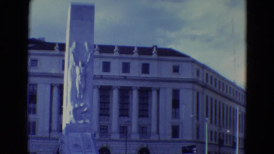 1969 Diller, Nebraska 8mm frame showing a classical-style columned building and tall monument from a visitor-shot angle.