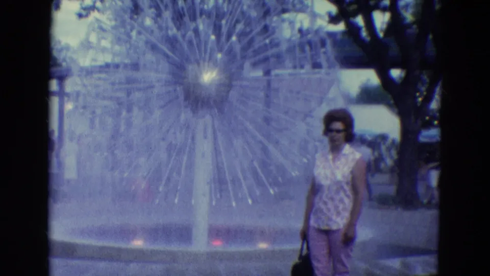 The woman appears at the right of the Diller, Nebraska fountain scene, holding a purse as water jets radiate behind her.