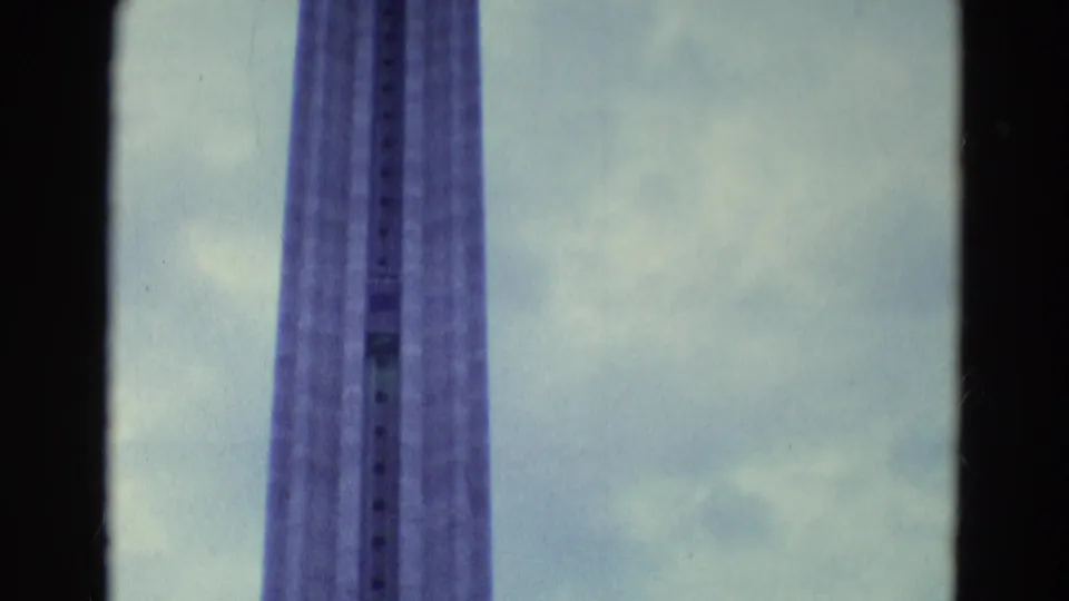 A final view keeps the tall lift structure centered, with cloudy sky and 8mm film texture visible around the frame.