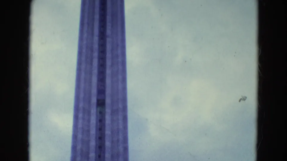 A centered 8mm view of the upper tower shaft, with cloudy sky and visible film grain.