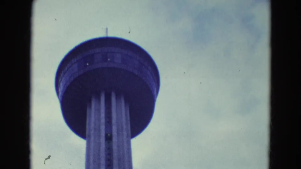 Final 1969 Diller, Nebraska frame holds on the tower's circular deck and vertical supports against a muted cloudy sky.