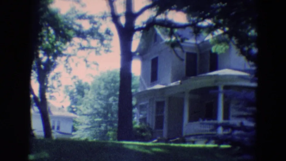 End of the 1969 Diller, Nebraska pan with the white house at right, trees overhead, lawn, and a distant structure.