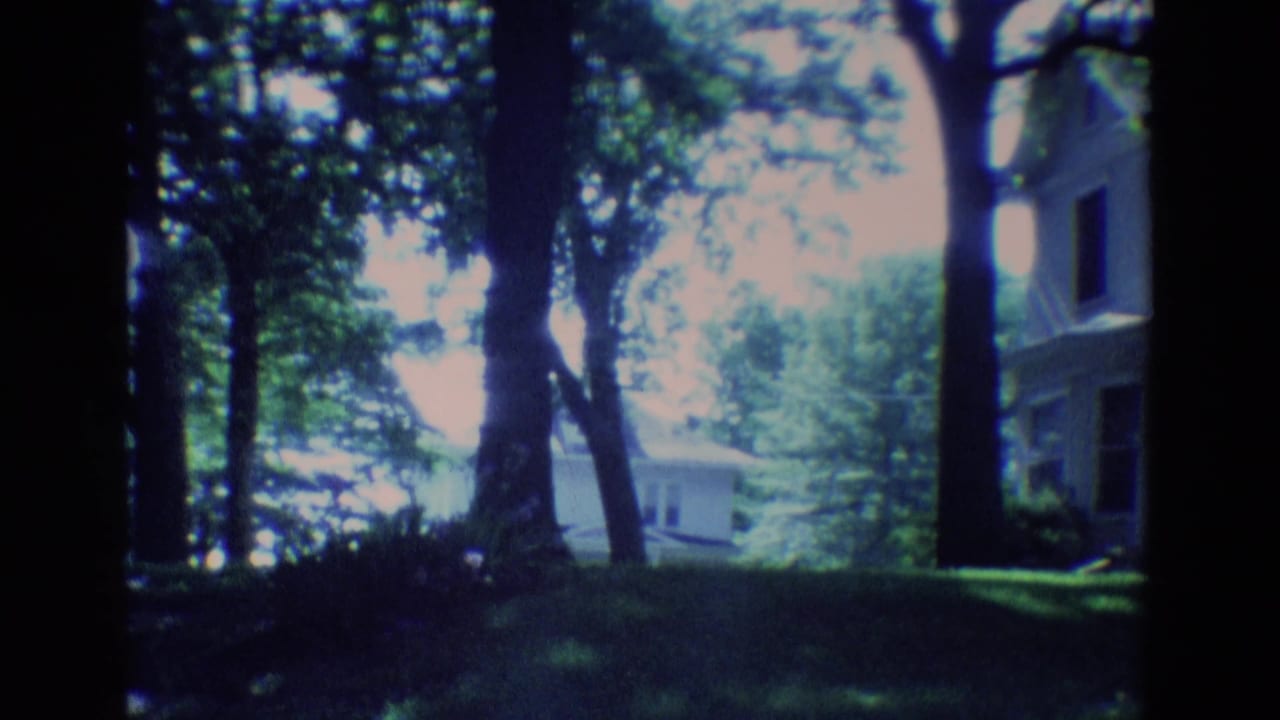 1969 Diller, Nebraska 8mm frame with mature trees, shaded lawn, part of a house, and a small structure beyond the yard.