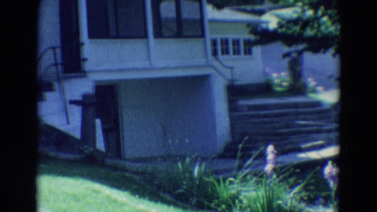 White house exterior with front steps, lawn, and garden plants.