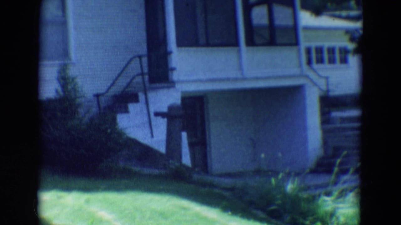 White house exterior with curved railings, steps, grass, and shrubs.