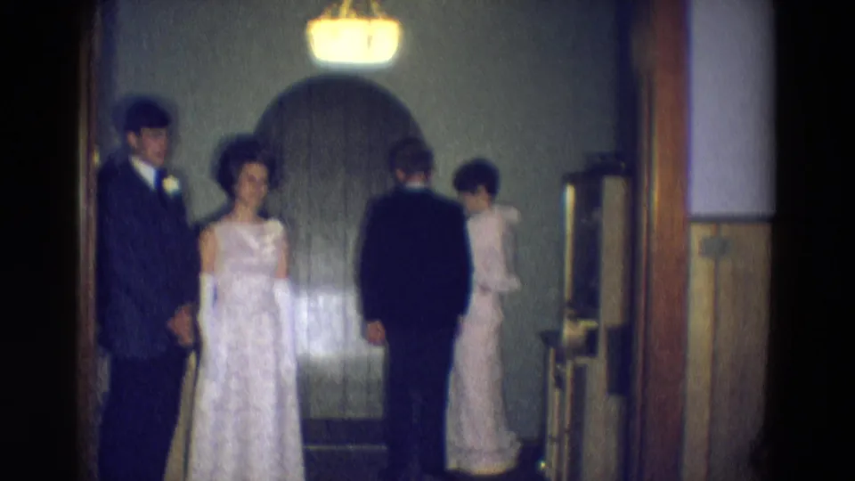 In the 1969 Diller footage, a man in a dark suit turns toward a woman in a light dress as another formal couple remains at left.