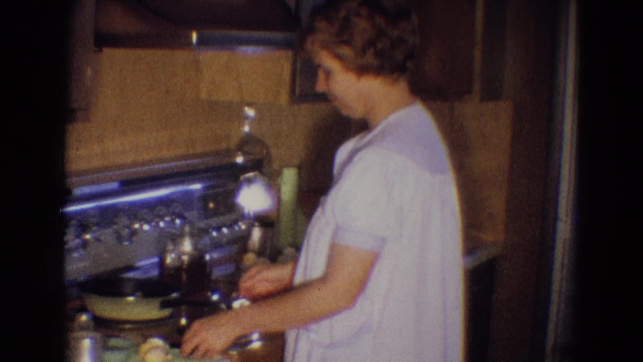 A woman in a white gown works at a kitchen stove in Diller, Nebraska, with cookware and wood cabinetry visible around her.