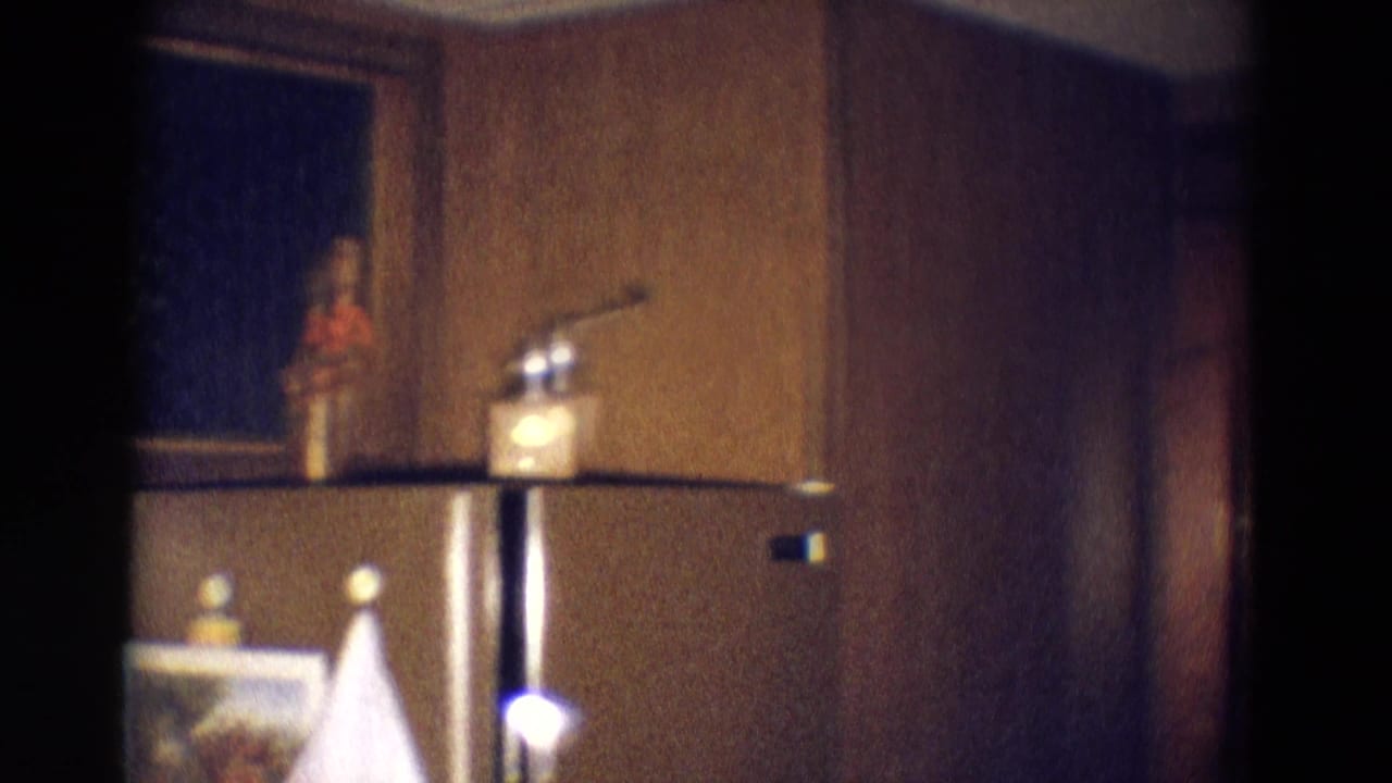 1969 Diller, Nebraska interior frame with a refrigerator, wood paneling, dark opening, and small objects on top in low household light.