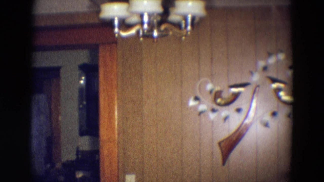 Wood-paneled room wall with ceiling light, abstract wall decor, and a doorway edge.