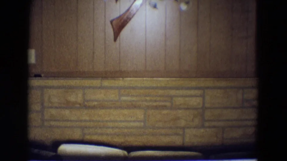 1969 Diller, Nebraska interior view with wood paneling, stone wainscot, partial wall decoration, and dark seating below.