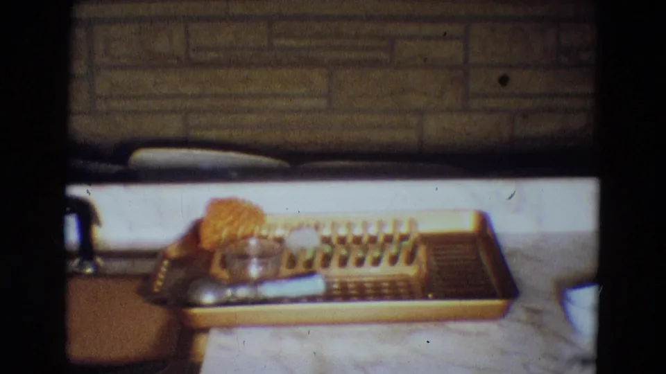1969 Diller, Nebraska recreation-room counter with an empty serving tray, orange sponge, dish-rack-like items, and stone wainscot behind.