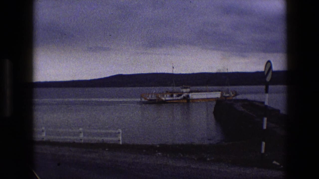 Yellow and white ferry beside a stone pier across calm water under dark clouds.