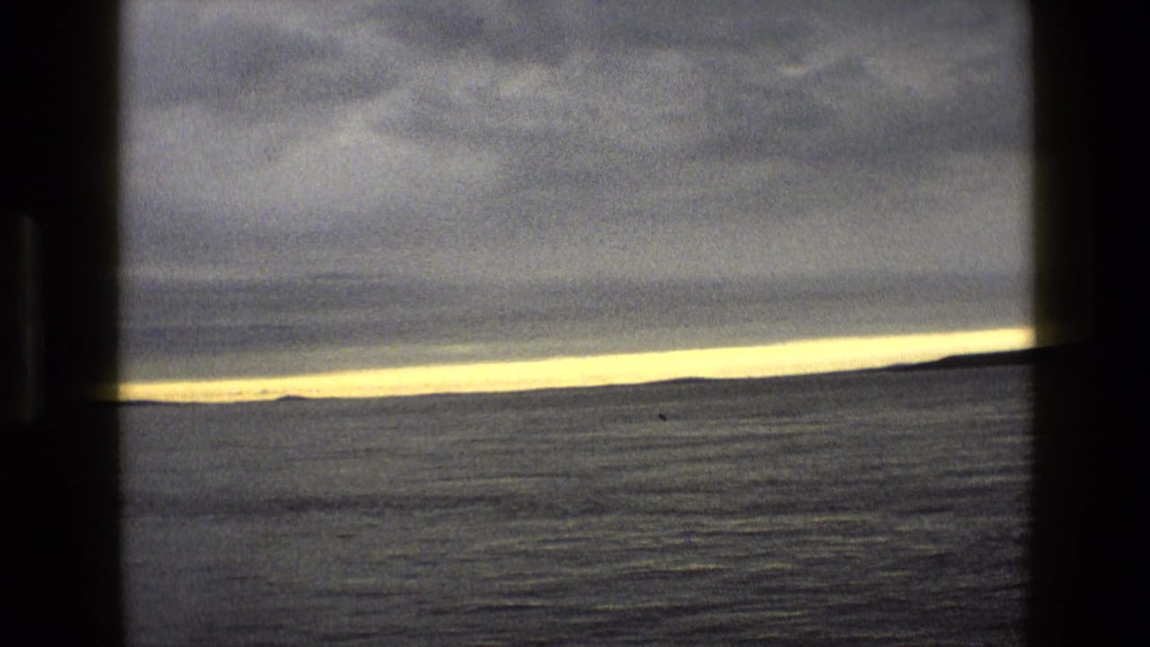 Open water beneath heavy clouds with a thin golden band at the horizon.
