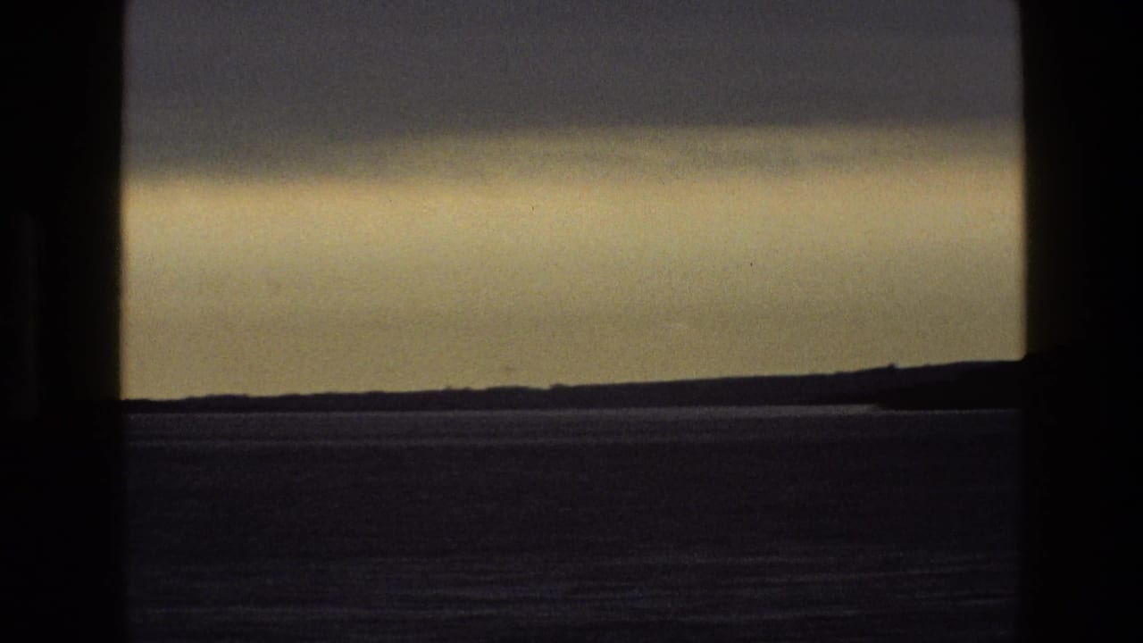 Dark window frame around a hazy horizon and flat landscape or water.