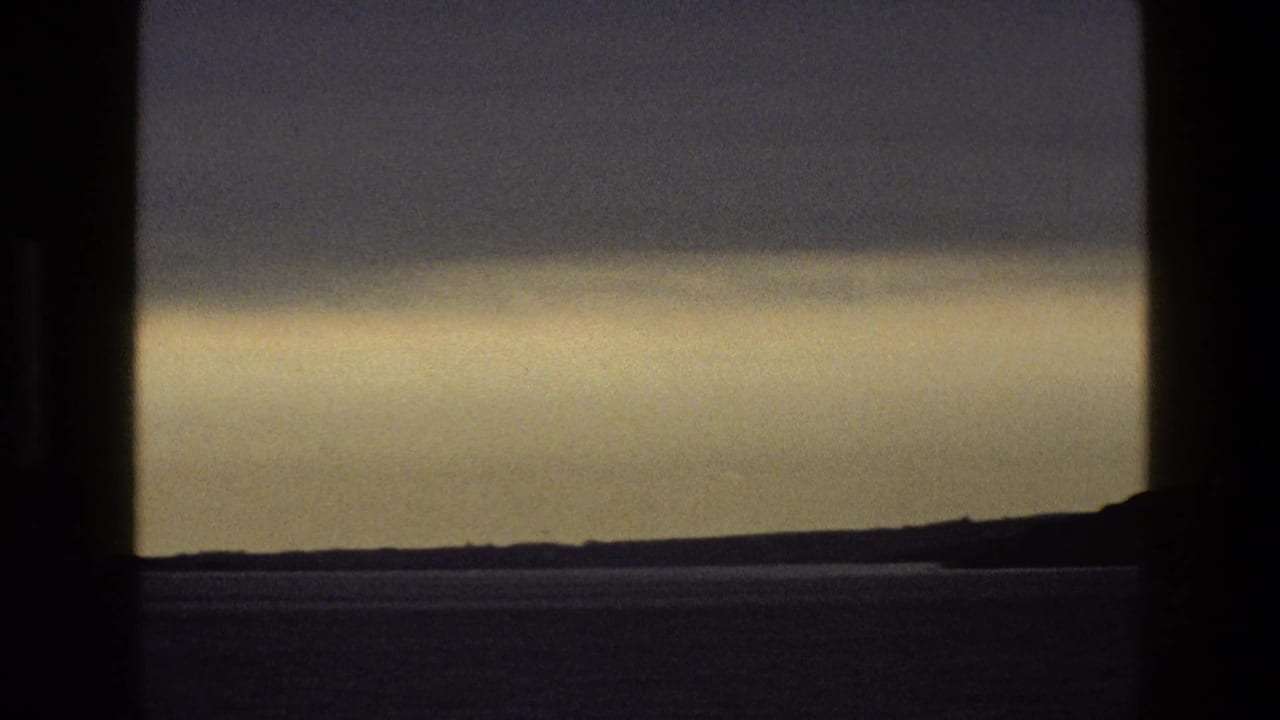 Hazy sky and distant low horizon divided by a dark vertical window bar.