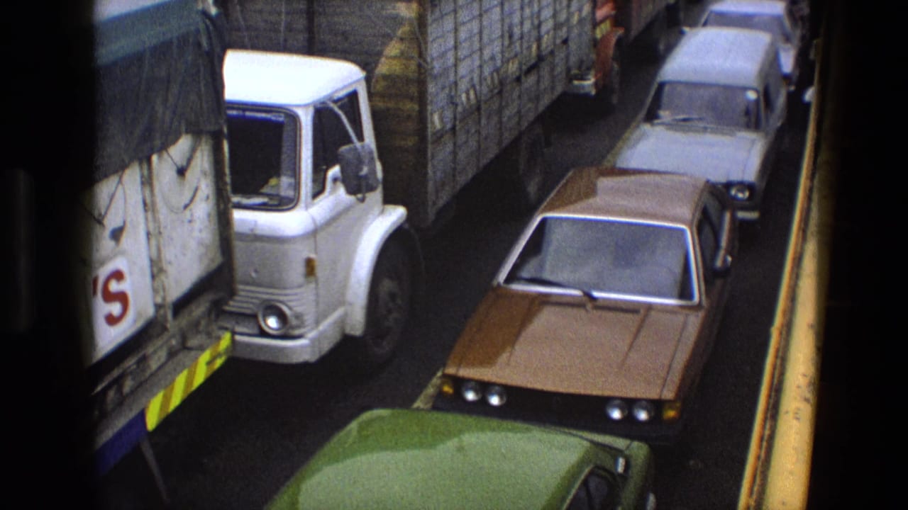 White covered lorry and brown sedan stopped beside a roadside barrier.
