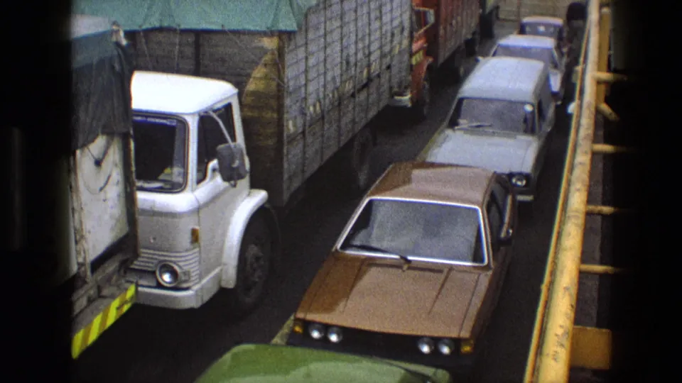 End frame of 1969 England 8mm traffic footage, showing a white covered lorry and several cars in a tight lane.