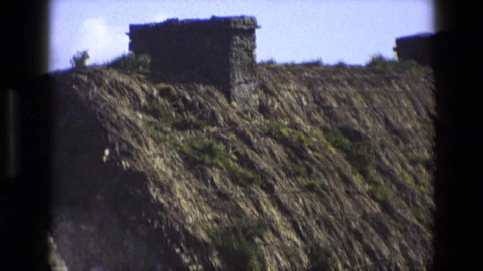 1969 England frame with a soft, close view of the thatched roof, chimney, and dark 8mm frame edge.
