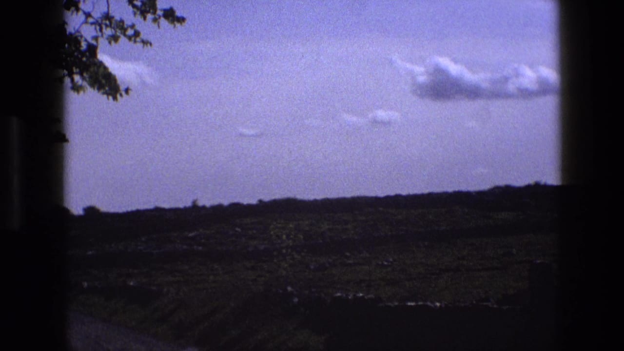 1969 England rural landscape with a broad sky, low fields, and dark side borders suggesting a moving window view.