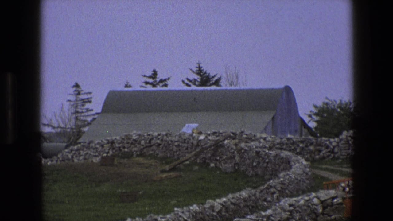 Rural English farm scene from 1969 showing a curved-roof barn, stone walls, trees, and a small orange structure near the lower edge.