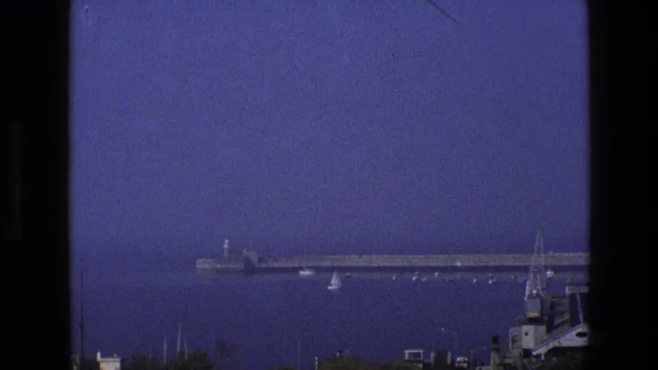 A later frame shifts toward the pier and small boats on the water, with part of a building or roofline entering at lower right.
