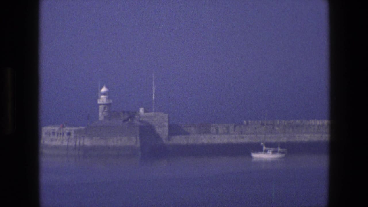 Coastal fort and lighthouse with a small boat crossing the harbor.