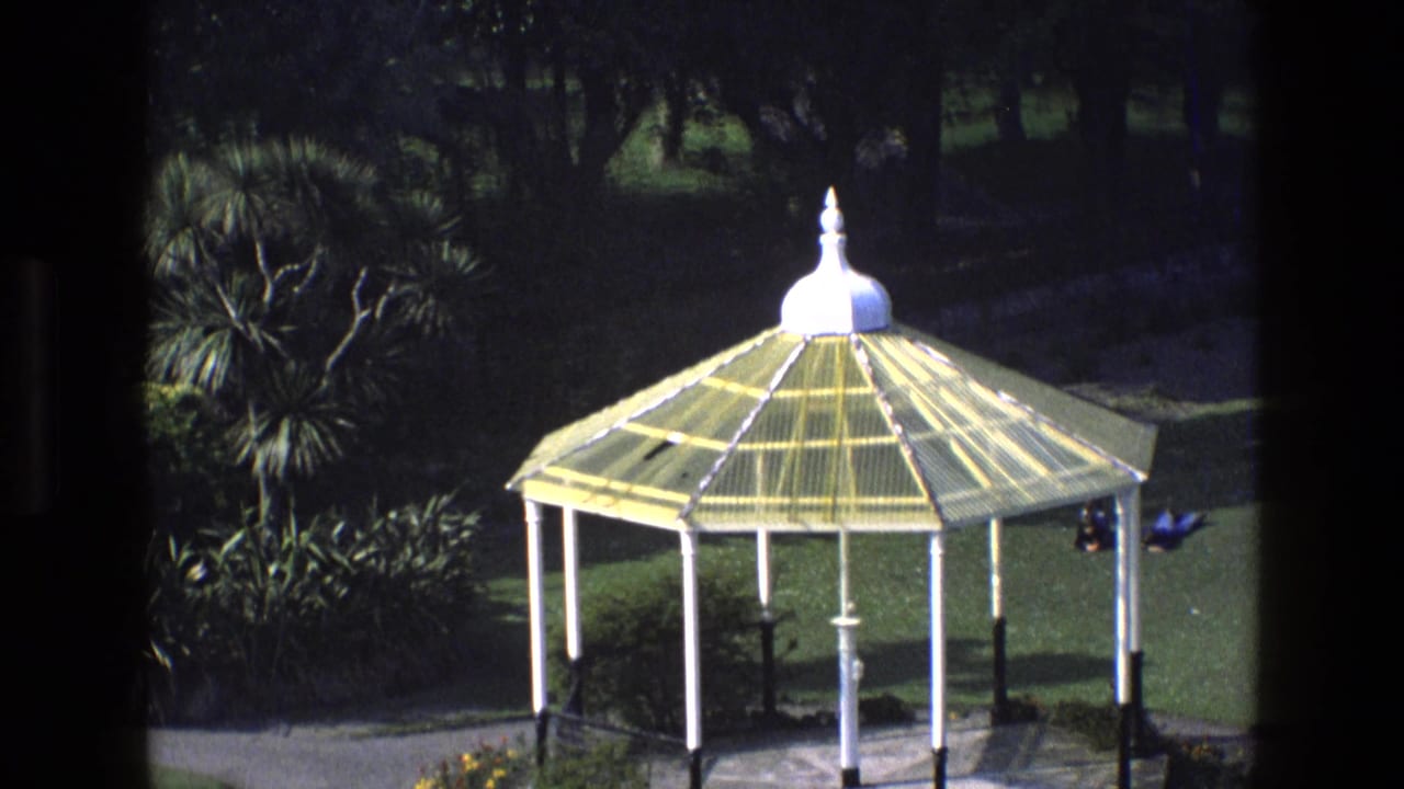 Bandstand with yellow roof in a landscaped park, seen from above.