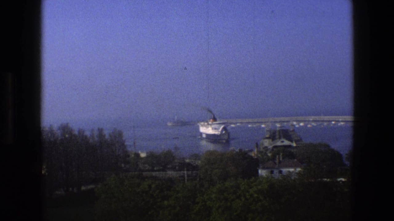 A large passenger ship sits farther out in an English harbor view, with marina structures and trees below the frame.