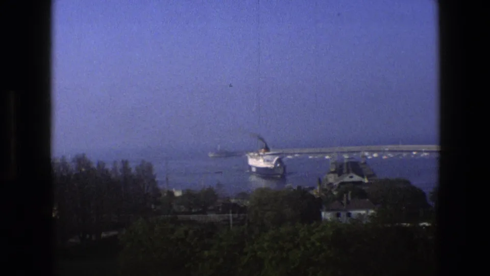 A large passenger ship sits farther out in an English harbor view, with marina structures and trees below the frame.
