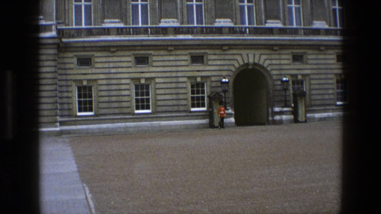 1969 England 8mm frame showing a Queen's Guard at attention near a sentry box outside a stone palace facade.