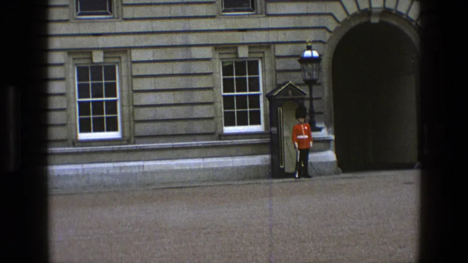 1969 England 8mm frame showing the ceremonial guard at attention near a sentry box on a stone palace exterior.