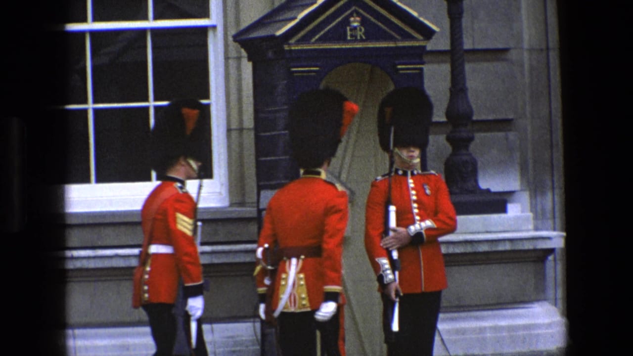 1969 England frame showing three British ceremonial soldiers in red tunics and bearskin hats near an ER-marked sentry box.