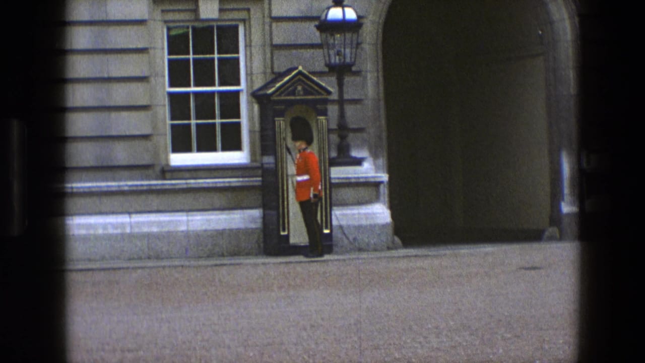 Uniformed guard standing near a sentry box outside a stone building.