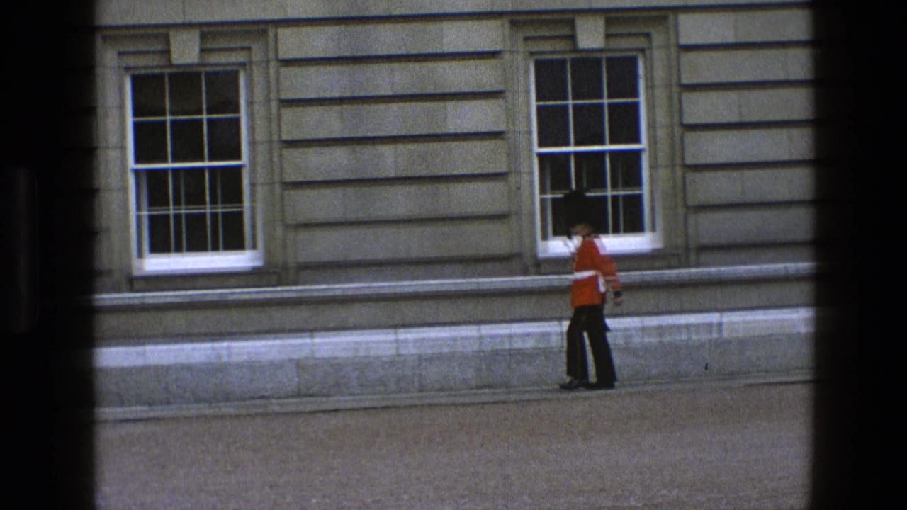 Ceremonial guard in red tunic marches along a stone building facade.