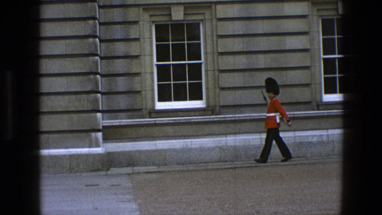 A British ceremonial guard in red uniform and tall black hat marches rightward along a pale stone building in the 1969 England clip.