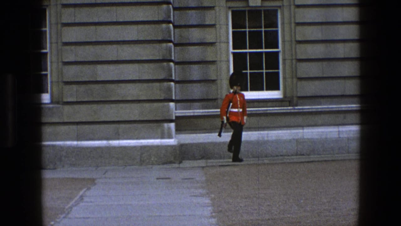 In England archival footage, a British guard in red tunic and black bearskin-style hat stands beside a stone facade with sash windows.