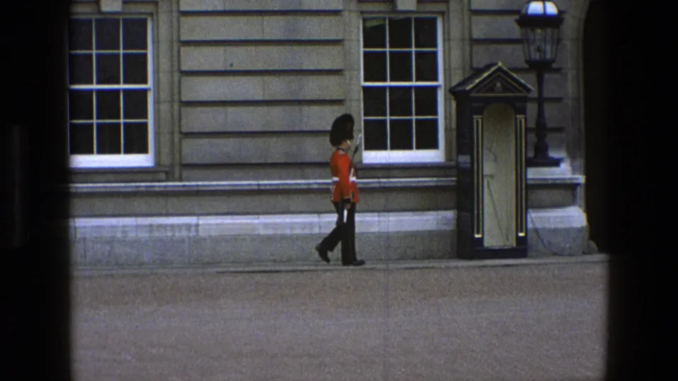 The guard continues past sash windows, with a sentry box and wall-mounted lamp visible in the courtyard setting.