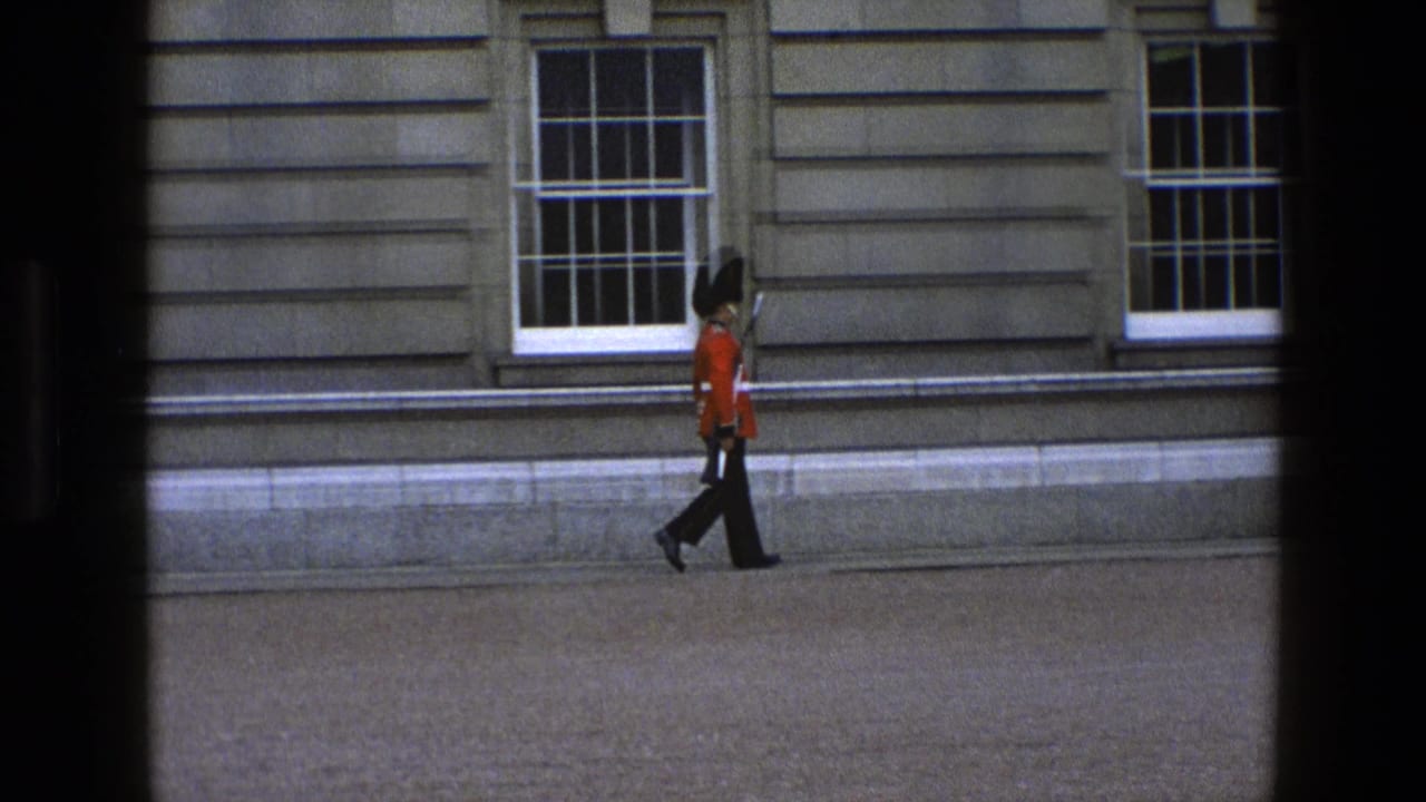 In 1969 England footage, a British ceremonial guard in red tunic and tall black hat walks past sash windows carrying a rifle.