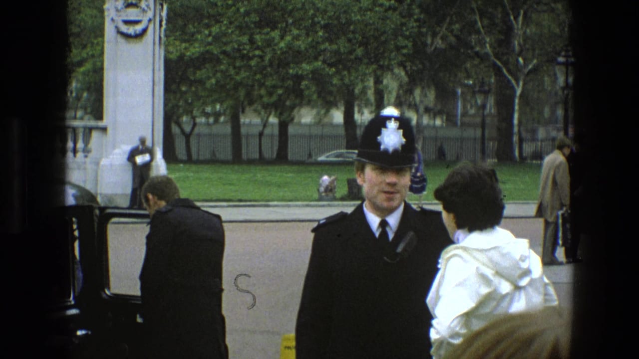 In 1969 England, a uniformed British police officer faces a person in a white coat near an open vintage car door on a tree-lined street.