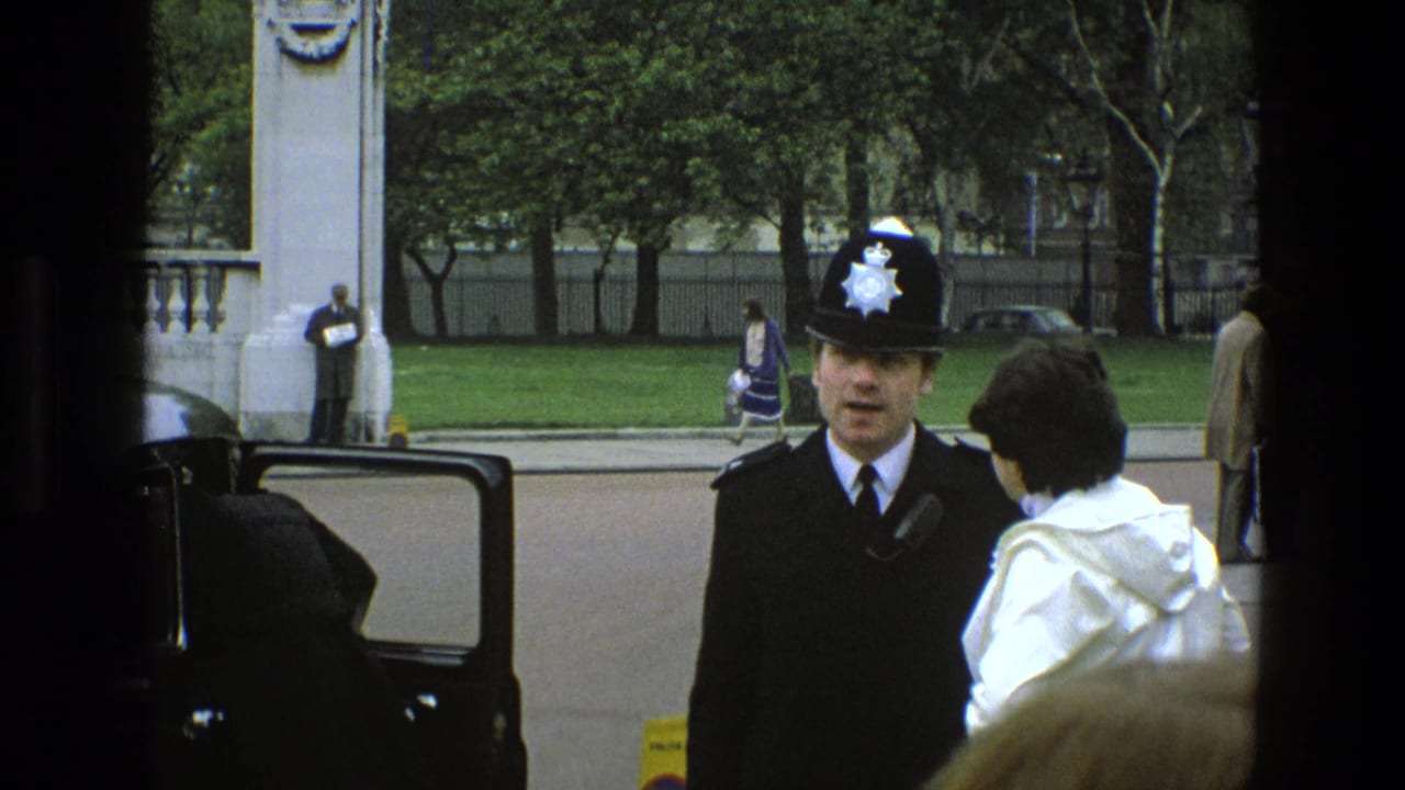 Police officer and white-coated person stand near a car with pedestrians behind them.