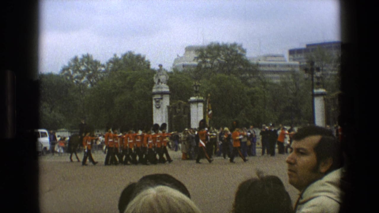 1969 England frame with a formation of guards in red uniforms and bearskin hats moving across a public ceremonial space.