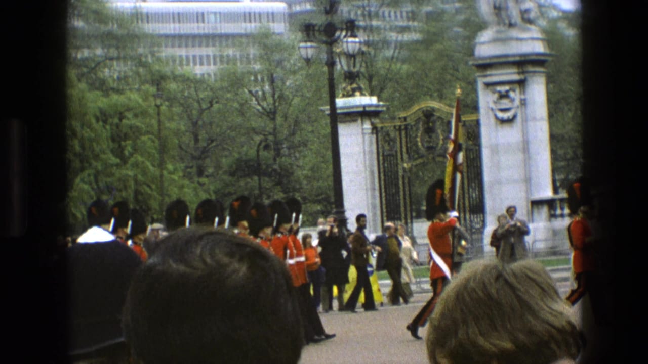 Guards and spectators stand near a gate with a flag and stone pillar visible.