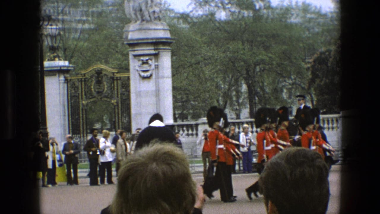 Mounted police and marching guards appear near ornate gates with spectators behind them.