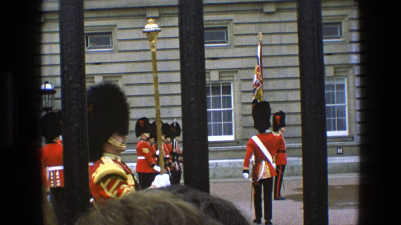 Uniformed guards stand and march near a palace facade, partly blocked by railings.