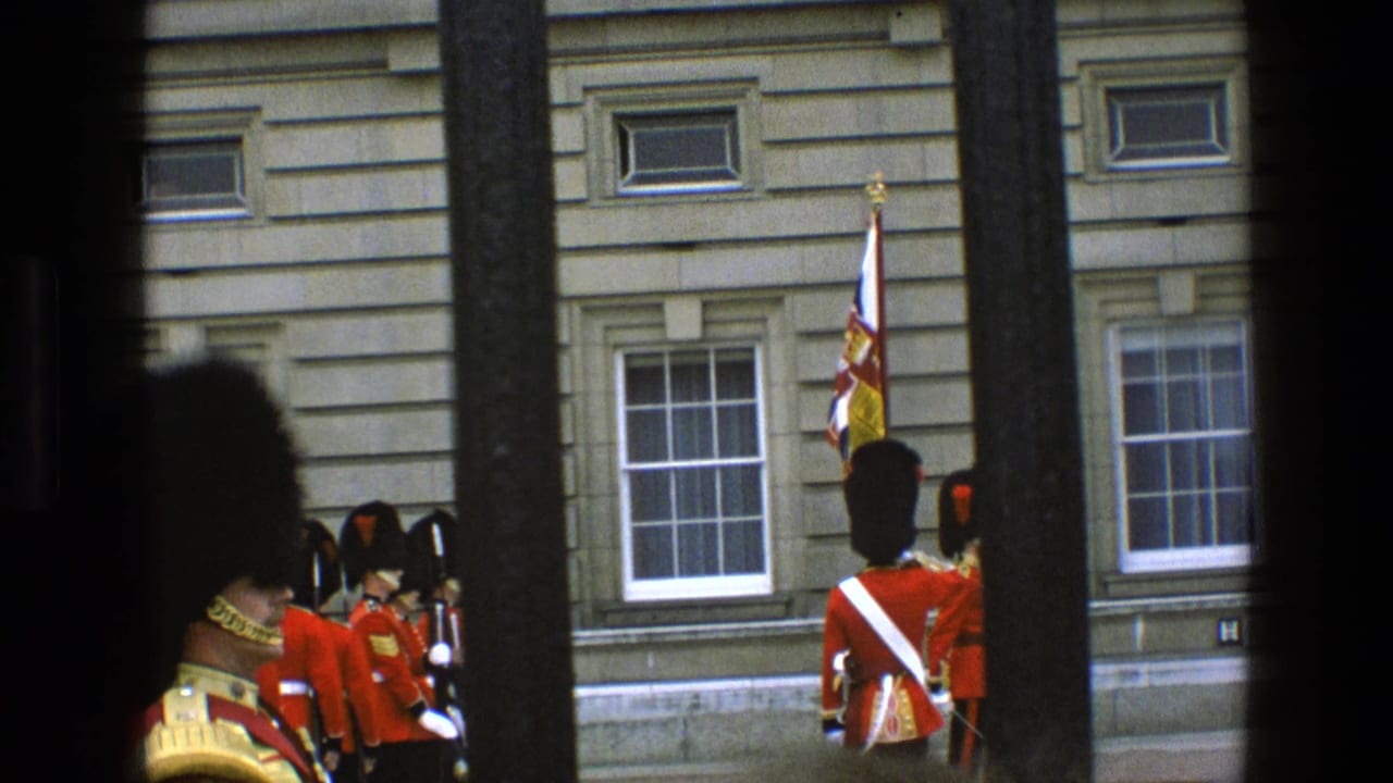 1969 England 8mm frame showing ceremonial guards in red uniforms near a stone palace facade, partly obscured by black bars.