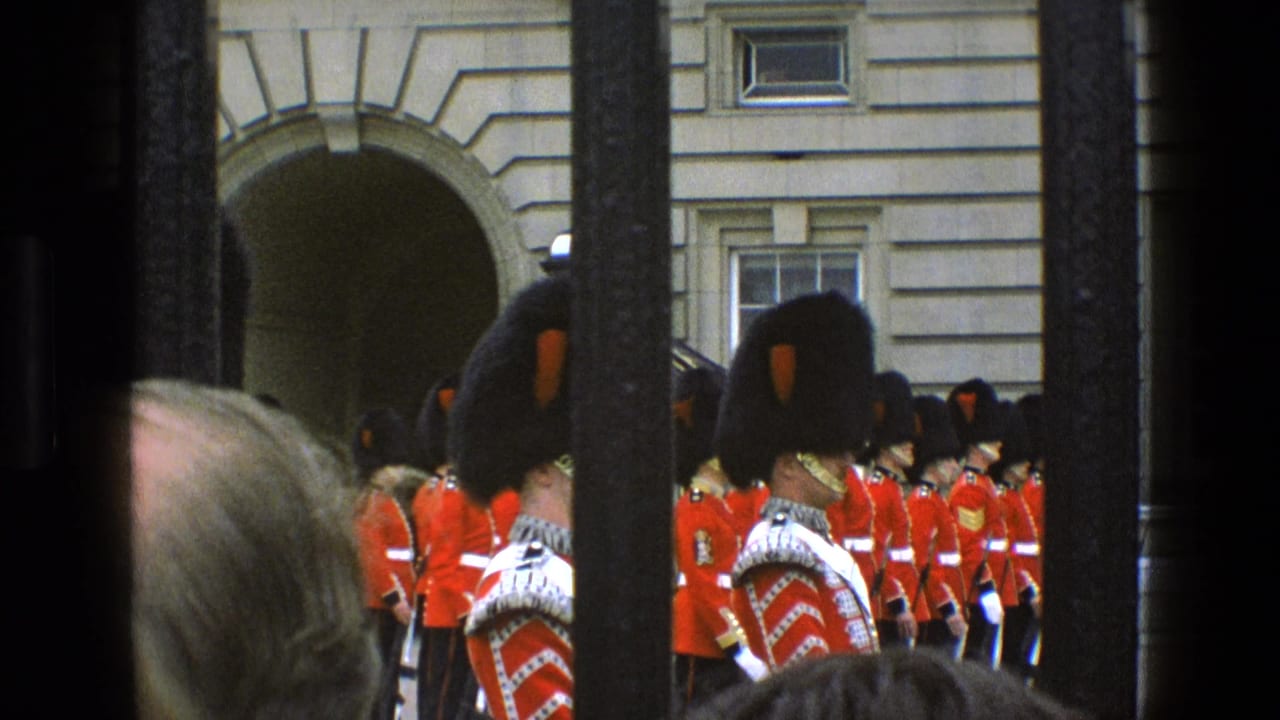 Final 1969 London frame shows Queen's Guard soldiers in red ceremonial dress at Buckingham Palace, with vertical bars and spectators partially obstructing the home-movie view.
